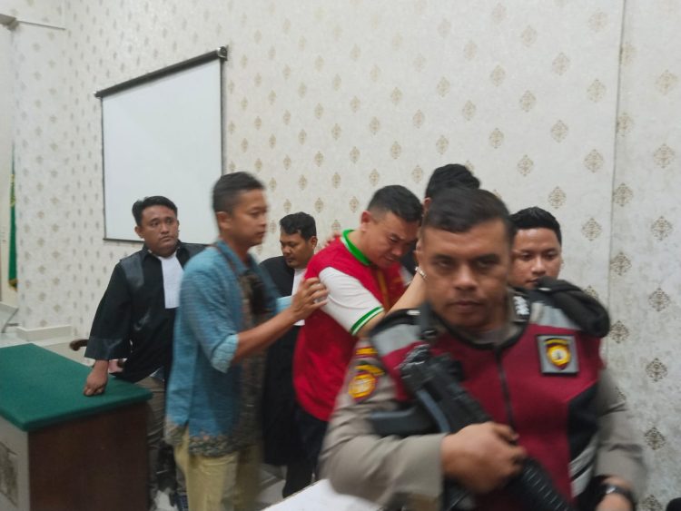 Terdakwa Joe berupaya menghindar dari kamera wartawan, usai dijatuhi hukuman seumur hidup. (foto: sinata/hendri)