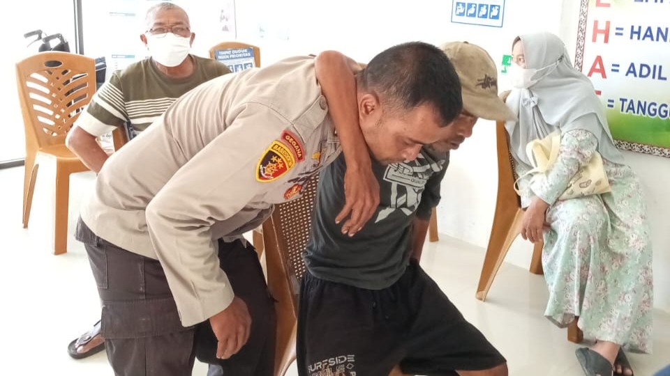 Bripka Asril memapah Bastian. (foto: ist)